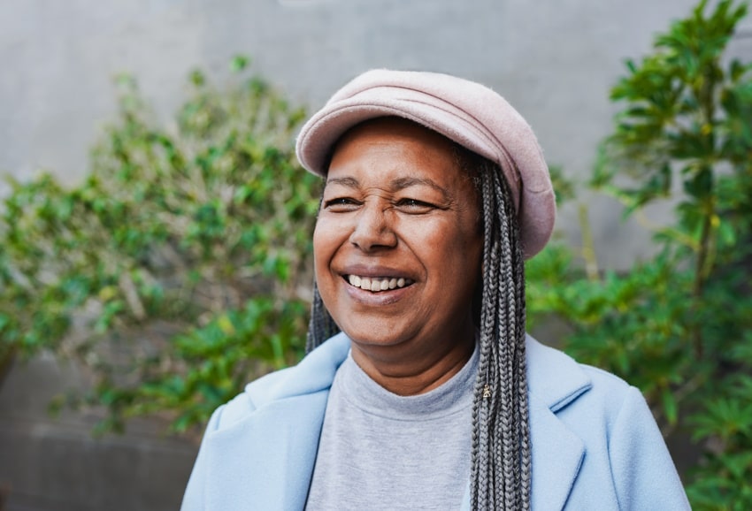 smiling african american female with pink hat oustide